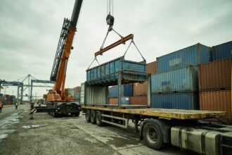 Grue industrielle chargeant des conteneurs par le dessus dans un port de fret international pour réduire les frais de manutention