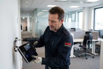 Technicien en sécurité installant un panneau de contrôle d'alarme sans fil dans un bureau professionnel moderne